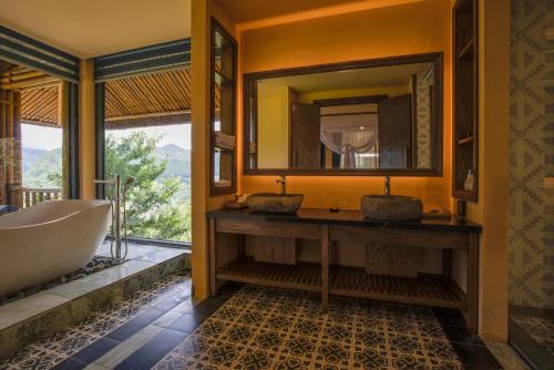a bathroom with two sinks and a tub and a mirror at Le Champ Tu Le Resort Hot Spring & Spa in Yen Bai
