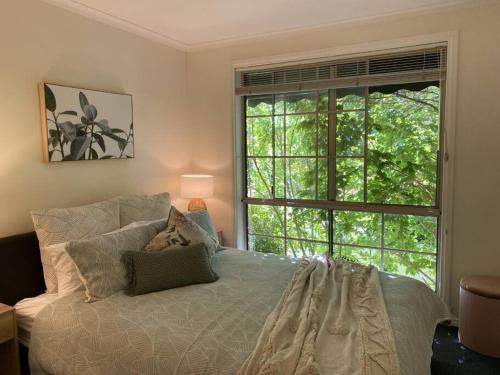 a bedroom with a bed and a large window at Yarra House - Comfortable 3 bedroom home close to everything! in Healesville
