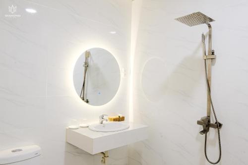 Baño blanco con lavabo y espejo en BB Hotel&Resort en Phu Quoc