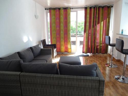 a living room with a couch and chairs and curtains at View on Ilot Fourneau in Le Morne