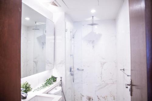 uma casa de banho branca com um chuveiro e um lavatório. em Plaza Damas by Plush em Kuala Lumpur