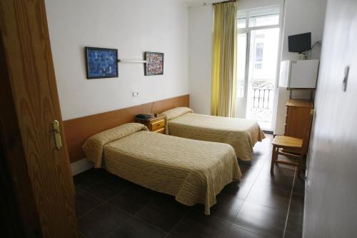 a hotel room with two beds and a window at Hostal San Fernando in Alicante