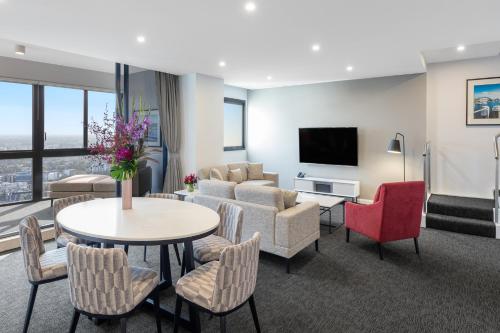 a living room with a couch and a table and chairs at Meriton Suites Kent Street, Sydney in Sydney
