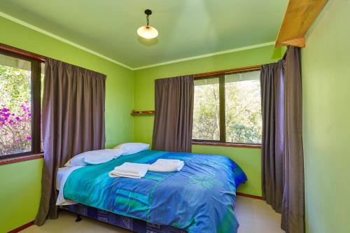 a bedroom with a bed with green walls and windows at Luigi's apartment in Rotorua