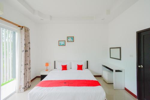 a bedroom with a white bed with red pillows at Baan Noppadol Hua Hin Resort in Hua Hin