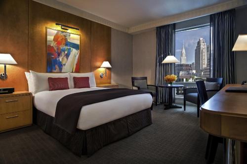 ニューヨークにあるソフィテル ニューヨークの大きなベッドとデスクが備わるホテルルームです。