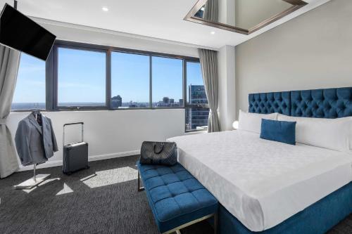 Meriton Suites Kent Street, Sydney في سيدني: غرفه فندقيه بسرير وكرسي ازرق