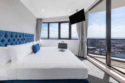a hotel room with a large bed and a large window at Meriton Suites Kent Street, Sydney in Sydney