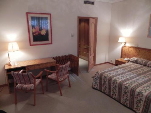 a hotel room with a bed and a desk and a table at Toros de Guisando in El Tiemblo