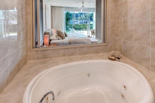 uma banheira na casa de banho com um espelho grande em Pavillions 1 - NEW Waterside Luxury with pool em Hamilton Island