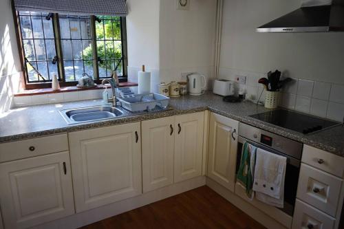 a kitchen with white cabinets and a sink and a window at Stunning Historic 2-Bed House in Shaftesbury in Shaftesbury