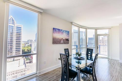 a dining room with a table and chairs and large windows at Uptown Charlotte 2BR Furnished Apartments apts in Charlotte