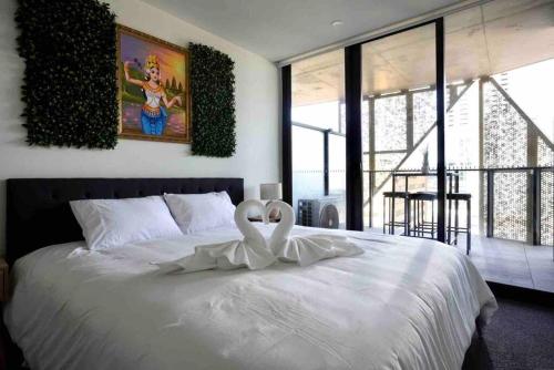 a bedroom with a white bed with two swans on it at City Zen Apartment-Gym-BBQ in Adelaide