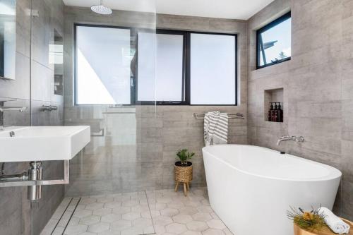 a bathroom with a large white tub and a sink at Canopy II - Beach House in the heart of Byron Bay in Byron Bay