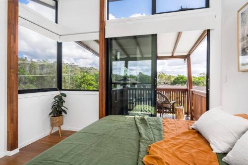 a bedroom with a bed and large windows at Canopy II - Beach House in the heart of Byron Bay in Byron Bay