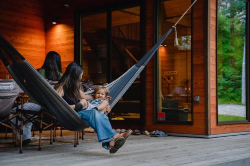 a woman sitting in a hammock holding a baby at Hygge Chalet Hakuba in Hakuba