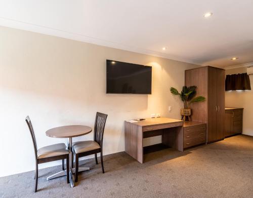 a room with a table and chairs and a television on the wall at Parkes International in Parkes