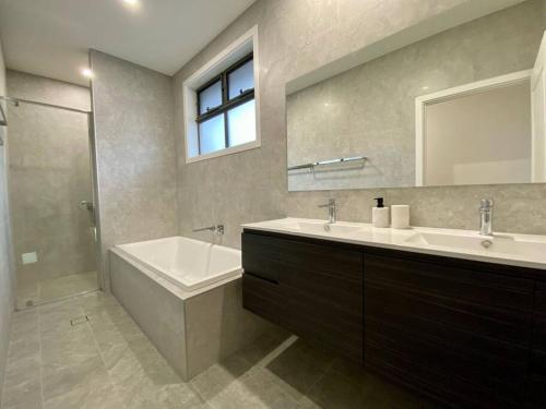 a bathroom with a sink and a tub and a mirror at New Spacious Luxury 5 Bedroom Mansion in Unley in Unley