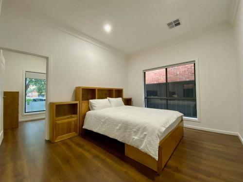 a bedroom with a large bed and two windows at New Spacious Luxury 5 Bedroom Mansion in Unley in Unley