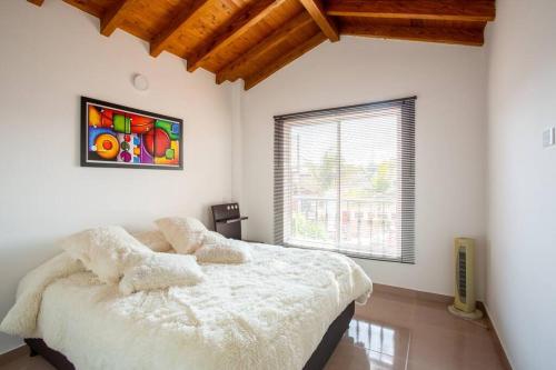 a bedroom with a large white bed with a window at Chalet Bajo el Cielo in Carmen de Viboral