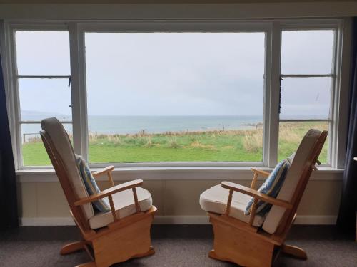two rocking chairs sitting in front of a window at Best Bay Views in Colac Bay