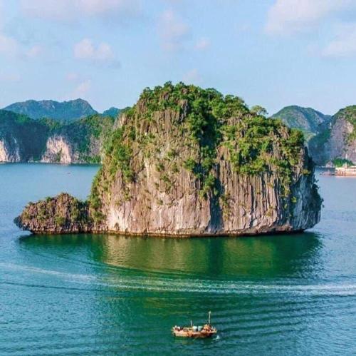 un bateau dans l'eau en face d'une île dans l'établissement Bee lucky homestay cat ba Island, à Xuan Dam