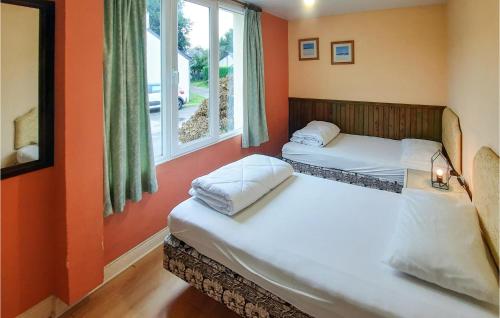 twee bedden in een kamer met oranje muren en een raam bij 2 Bedroom Stunning Home In Bannalec in Bannalec