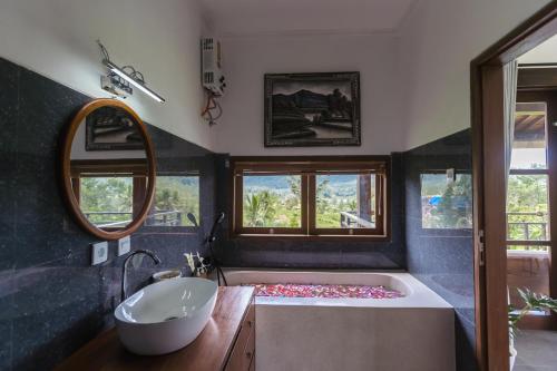 a bathroom with a tub and a sink and a mirror at Ume Dukuh Home Sidemen in Sidemen