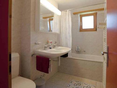 y baño con lavabo, aseo y espejo. en Ferienwohnung Profos 54002B, en Ruschein