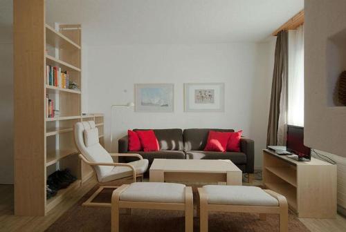 - un salon avec un canapé et des oreillers rouges dans l'établissement Ferienwohnung Profos 54002B, à Ruschein