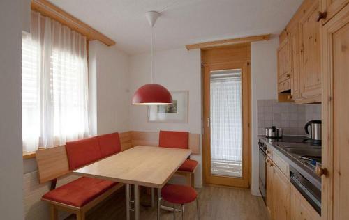 una pequeña cocina con mesa de madera y sillas rojas en Ferienwohnung Profos 54002B, en Ruschein