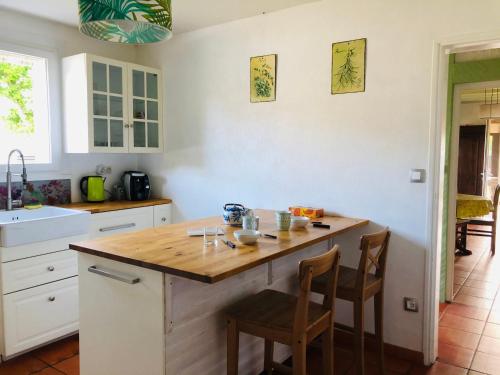 une cuisine avec un îlot en bois et 2 chaises dans l'établissement Studio dans belle maison landaise, à Arès