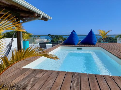 a swimming pool with blue pillows on a wooden deck at Les Terrasses du Bénitier in La Gaulette