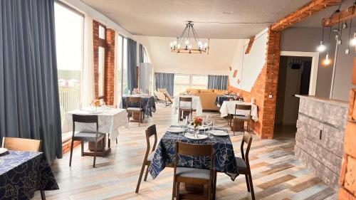 a dining room with tables and chairs and windows at Hotel West Face in Kutaisi