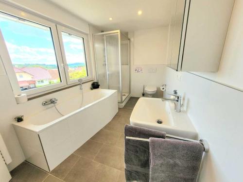 a bathroom with a tub and a sink and a bath tub at Cozy & Modern 4 Room Flat near Hanau in Gedern