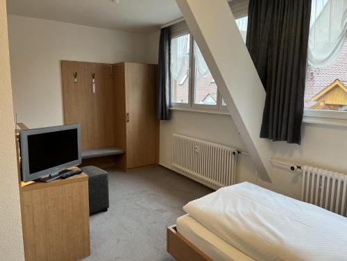 - une chambre avec un lit, une télévision et un escalier dans l'établissement Hotel Bären, à Villingen-Schwenningen