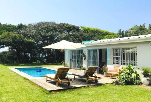 a house with a pool and two chairs and an umbrella at Sky Tyde's Beach House in Port Shepstone