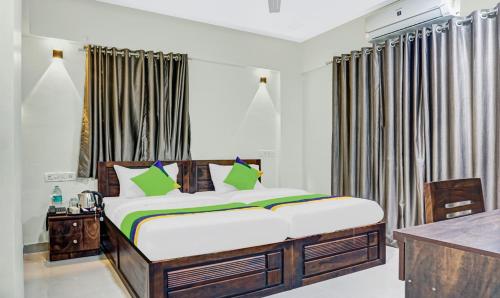 a bedroom with a large bed with green pillows at Treebo Tulip in Pune