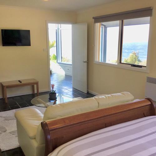 un salon avec un canapé et une grande fenêtre dans l'établissement Skyescape on Northshore, à Table Cape