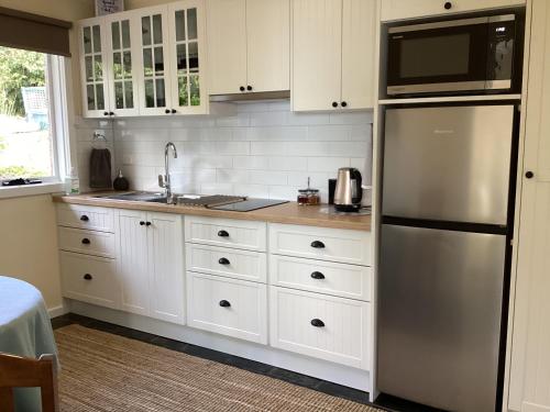 a kitchen with white cabinets and a stainless steel refrigerator at Skyescape on Northshore in Table Cape