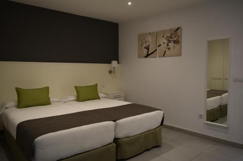 a bedroom with a large bed with green pillows at Apartamentos Hotel Parque in Las Palmas de Gran Canaria
