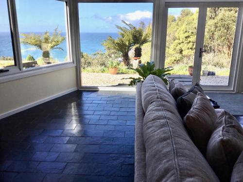a living room with a couch and views of the ocean at Skyescape on Northshore in Table Cape