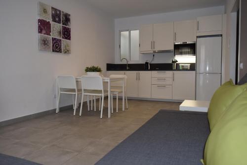 a kitchen with white cabinets and a table and chairs at Apartamentos Hotel Parque in Las Palmas de Gran Canaria