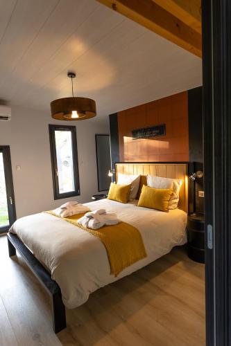 une chambre avec un grand lit avec des oreillers jaunes dans l'établissement Le Domaine de l'étang fourchu, à Florimont