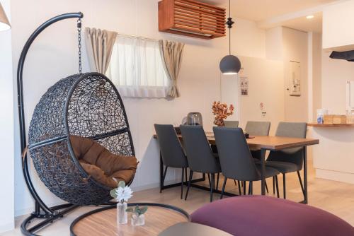a swing chair in a dining room with a table at Bijou Suites Sorriso in Osaka