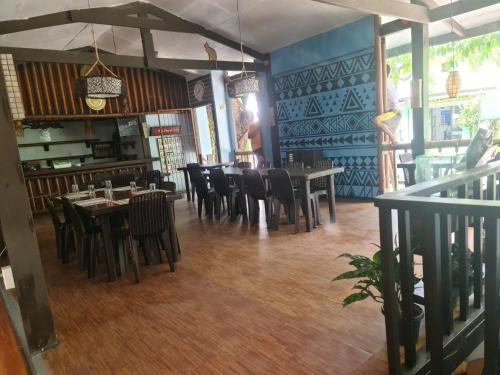 um restaurante com pisos e mesas e cadeiras de madeira em Coron town travellers inn em Coron