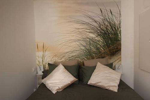 a couch with pillows in a room with plants at Appart neuf, parfaitement situé 6min CV-8min GARE in Arles