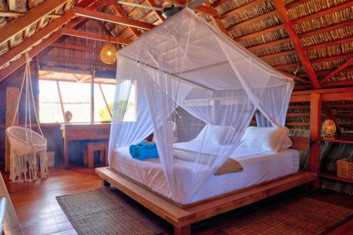 a bedroom with a canopy bed in a room at Loedi Bungalows Rote in Nembrala