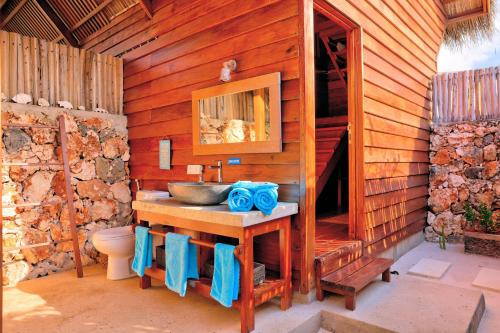 a bathroom with a sink in a wooden wall at Loedi Bungalows Rote in Nembrala