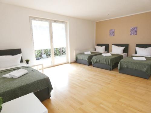 Cette chambre comprend deux lits et une grande fenêtre. dans l'établissement SUNNYHOME Monteurwohnungen und Apartments in Weiden, à Moosbürg